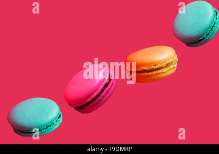 Différents types de macarons dans motion relevant sur fond rose clair, gros plan Banque D'Images