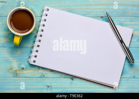 Spirale Blanc carnet d'art contre contre bois grunge avec une tasse de café et un stylo Banque D'Images