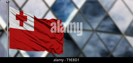 Tonga drapeaux dans le vent contre floue bâtiment moderne. Concept d'entreprise. Thème de la coopération nationale. Banque D'Images