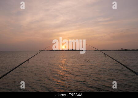 Et naturel magnifique coucher de soleil avec des nuages et des cannes à pêche dans l'arrière-plan, sur la côte de Jeddah, Arabie Saoudite Banque D'Images