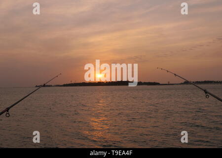 Et naturel magnifique coucher de soleil avec des nuages et des cannes à pêche dans l'arrière-plan, sur la côte de Jeddah, Arabie Saoudite Banque D'Images