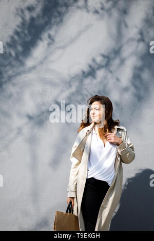 Une jeune femme, sympathique, pas une mince-dirigé musculation, promenades autour de la ville avec un package pour le shopping. Banque D'Images