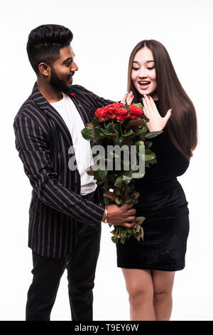 Ils sont aussi beaux que vous. La longueur totale de l'homme indien donnant un bouquet de roses rouges pour son asian woman on white background Banque D'Images