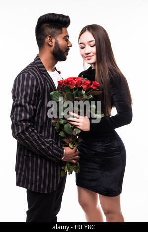 Ils sont aussi beaux que vous. La longueur totale de l'homme indien donnant un bouquet de roses rouges pour son asian woman on white background Banque D'Images