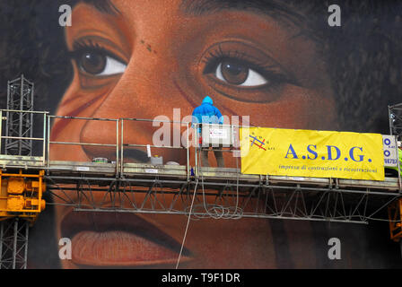 Agoch Jorit, 28, rue napolitaine est artiste de renommée internationale, père et mère néerlandaise. Il crée des peintures murales géantes sur les façades des immeubles de banlieue à travers le monde. Ses œuvres sont présentes à Buenos Aires, Córdoba, Aruba, Santiago du Chili, New York, Miami, Las Vegas, Los Angeles, San Francisco, Shenzhen, Gaza. En Italie Jorit est principalement actif à Naples où il fait d'immenses peintures sur façades aveugles des immeubles de banlieue et aussi dans le centre historique. Banlieue de Naples, bâtiments populaires de mauvaise réputation de Scampia trimestre. La peinture de Angela Davis. Banque D'Images