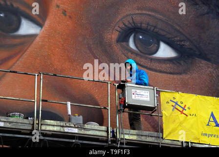 Agoch Jorit, 28, rue napolitaine est artiste de renommée internationale, père et mère néerlandaise. Il crée des peintures murales géantes sur les façades des immeubles de banlieue à travers le monde. Ses œuvres sont présentes à Buenos Aires, Córdoba, Aruba, Santiago du Chili, New York, Miami, Las Vegas, Los Angeles, San Francisco, Shenzhen, Gaza. En Italie Jorit est principalement actif à Naples où il fait d'immenses peintures sur façades aveugles des immeubles de banlieue et aussi dans le centre historique. Banlieue de Naples, bâtiments populaires de mauvaise réputation de Scampia trimestre. La peinture de Angela Davis. Banque D'Images