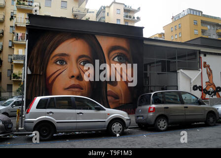 Agoch Jorit, 28, rue napolitaine est artiste de renommée internationale, père et mère néerlandaise. Il crée des peintures murales géantes sur les façades des immeubles de banlieue à travers le monde. Ses œuvres sont présentes à Buenos Aires, Córdoba, Aruba, Santiago du Chili, New York, Miami, Las Vegas, Los Angeles, San Francisco, Shenzhen, Gaza. En Italie Jorit est principalement actif à Naples où il fait d'immenses peintures sur façades aveugles des immeubles de banlieue et aussi dans le centre historique. Naples, quartier Vomero, Jorit peinture de Ilaria Cucchi, la soeur de Stefano Cucchi. Stefano a été tué en th Banque D'Images