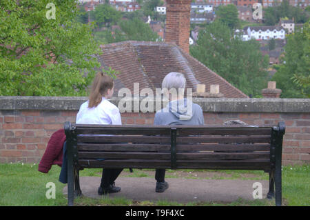 Vue arrière d'un Young boy and girl s'assit sur un banc à Bridgnorth, Shropshire, Angleterre Banque D'Images