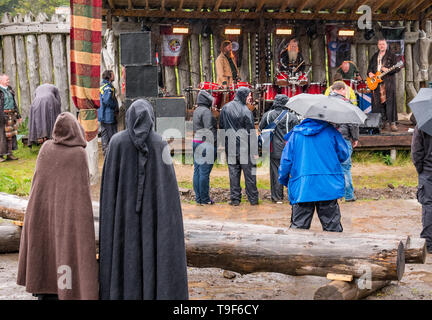 Duncarron Village médiéval, Carron Valley Forest, Lanarkshire, Écosse, Royaume-Uni, 18 mai 2019. Ouverture du Village Médiéval Duncarron : la confiance Clanranald ouvre une réplique grandeur nature d'un village fortifié médiéval typique d'un chef de clan écossais à sa résidence. Fort Duncarron open air museum comprend des bâtiments traditionnels. L'événement débute avec music band Saor Patrol, emmené par Charlie Allan, PDG de Clanranald Trust. Les gens vêtus de capes à capuchon médiéval regarder la performance Banque D'Images