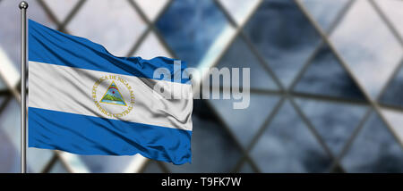 Nicaragua drapeaux dans le vent contre floue bâtiment moderne. Concept d'entreprise. Thème de la coopération nationale. Banque D'Images