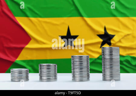 Froissé de Sao Tomé-et-Principe d'un drapeau à l'arrière-plan avec des rangées de pièces de monnaie pour financer et concept d'entreprise. L'économie d'argent. Banque D'Images