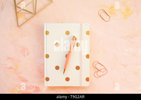 Le bloc-notes et stylo sur un espace de bureau, fond rose. Mise à plat, vue du dessus, les médias sociaux hero modèle d'en-tête, style de concept. Banque D'Images