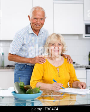 Portrait of mature couple à table de cuisine du remplissage des documents Banque D'Images