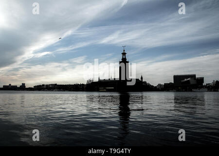 La silhouette de l'hôtel de ville de Stockholm contre le soleil de l'après-midi. Le bâtiment sombre se reflète dans l'eau. Banque D'Images