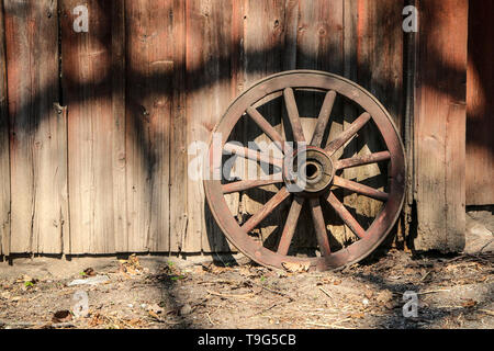 La vieille roue en bois à partir d'un panier est debout près de la maison de la façade 5ème planches. Banque D'Images