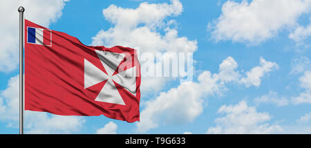 Wallis et Futuna drapeaux dans le vent contre blanc nuageux ciel bleu. Concept de diplomatie, de relations internationales. Banque D'Images