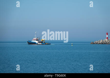 La mer remorqueur sort du port à côté du phare. Port de mer sur une journée ensoleillée. Banque D'Images