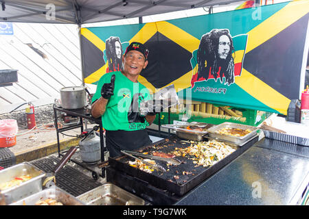 McDonough, Géorgie - 18 mai 2019 : Un vendeur de nourriture nourriture jamaïcaine prépare pour les clients à la 42e Festival annuel de géranium. Banque D'Images