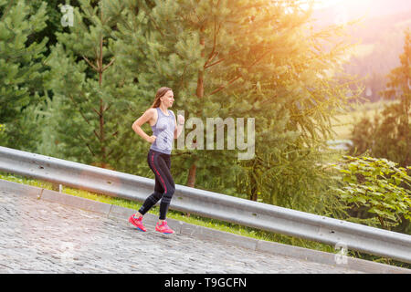 Young woman running bas sur la route pavée. Image de fille jogging with copy space Banque D'Images