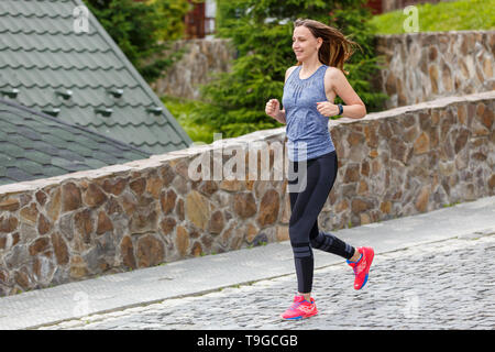 Young woman running bas sur la route pavée. Image de fille jogging with copy space Banque D'Images