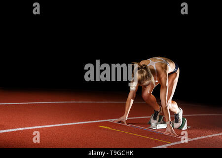 Coureuse à partir de l'athlète running course de sprint sur la piste. L'athlétisme athletic image concept isolated on black with copy space Banque D'Images