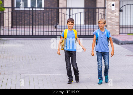 Deux shoolboys heureux avec sacs à dos aller à l'école le matin Banque D'Images