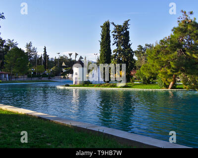 Beau moulin blanc sur la petite île à l'intérieur d'un lac du parc. Alsos Filadelfeias, Athènes, Grèce. Banque D'Images