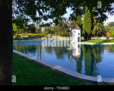 Beau moulin blanc sur la petite île à l'intérieur d'un lac du parc. Alsos Filadelfeias, Athènes, Grèce. Banque D'Images