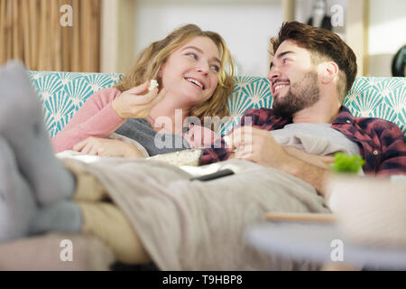 Couple chatting sur le canapé se blottit sous une couverture Banque D'Images