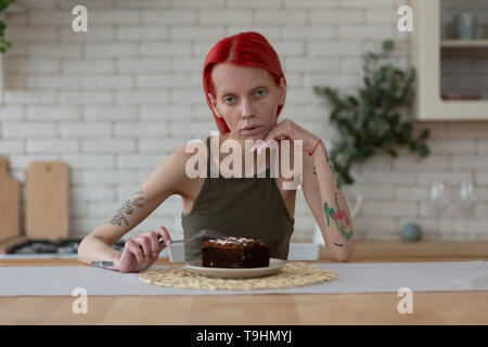 Femme avec trouble de l'alimentation s'asseyant à côté de la plaque avec cake Banque D'Images