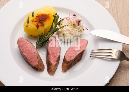 Selle d'agneau viande avec pommes de terre frites sur une assiette Banque D'Images