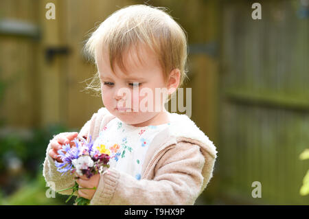 Jeune bébé fille de deux ans et demi de préparation de l'âge de fleurs jardin de Gaulle Charles Banque D'Images