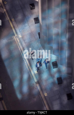 Depuis une vue aérienne vers les chiffres de la petite entreprise marche à travers la lumière bleue dans la ville de Londres, la capitale antique du quartier financier, le 13 mai, à Londres, en Angleterre. Banque D'Images