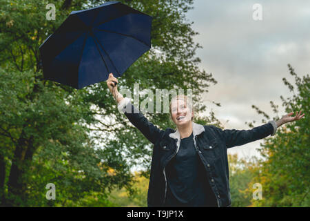 Jeune femme contient jusqu'son parapluie et cheers Banque D'Images