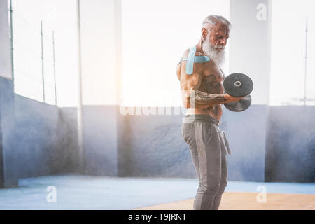 Barbe Fitness man doing biceps curl exercer à l'intérieur d'une salle de sport - Tatouage formation senior avec haltères en centre de bien-être Banque D'Images