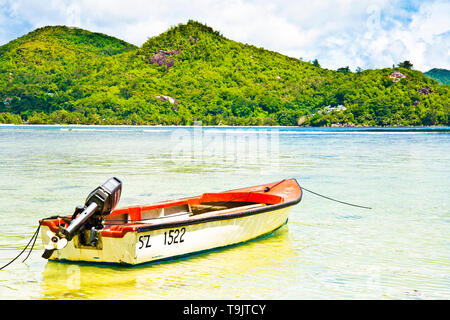 Petit bateau de pêche peint en rouge et blanc coloré avec ancrage de moteur extérieur dans l'océan turquoise Banque D'Images