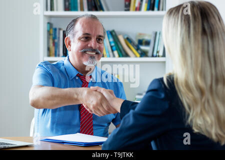 Poignée de senior businessman and woman après l'entrevue d'emploi au bureau de l'entreprise Banque D'Images