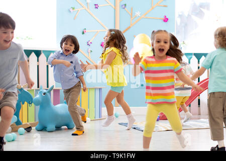 Groupe d'enfants heureux de garçons et de filles courir à la garderie. Les enfants jouent dans le jardin d'enfants Banque D'Images