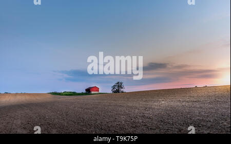 Ferme idyllique avec grange rouge dans la campagne du Maryland avec champs labourés au coucher du soleil pendant le printemps Banque D'Images