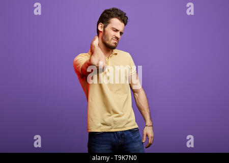 Beau jeune homme aux yeux clos , souffrant de douleur au cou prolongée. la photo en gros. studio shot. malheureux après une mauvaise position de sommeil Banque D'Images