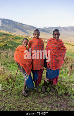 Les garçons dans l'école de maasai avec leurs costumes traditionnels boma dans la distance, la Ngorongoro Conservation Area, Tanzania Banque D'Images
