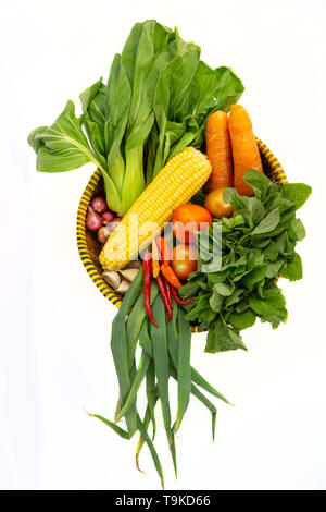 Vue de dessus de divers légumes frais dans un panier de bambou isolé sur fond blanc Banque D'Images