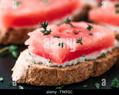 Toasts avec du fromage à pâte molle, de la pastèque et thym frais.salé sucré,fromage pastèque et épicé sur croquant de thym pain grillé tranches. Idée et recette pour un petit-déjeuner sain, inhabituelle en goûter d'été Banque D'Images