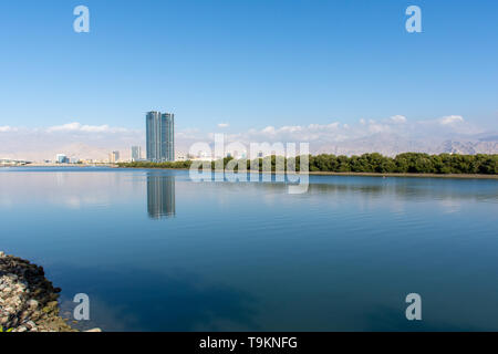 Ras al Khaimah vue depuis la Corniche vers la Julphar Towers sur la gauche, centre-ville, le crisp montagnes à la fin de l'hiver le soleil l'après-midi. Banque D'Images