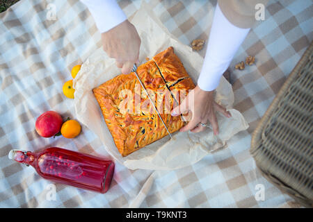 Mains de femme avec des morceaux de tarte aux pommes sur une couverture à carreaux. Vue d'en haut Banque D'Images