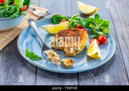 Gâteau de poisson Saumon maison avec salade fraîche garnie avec du citron Banque D'Images