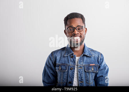 L'horizontale close up portrait of happy african joyeux gars en veste en jean lunettes tout sourire avec des dents de rire sur ba gris Banque D'Images