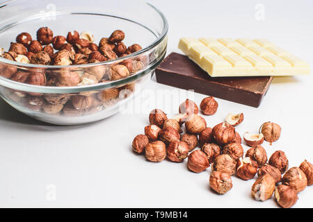 Bol de cristal isolé aux noisettes, chocolat blanc et chocolat au lait ou noir contre blanc. Noix décortiquées Banque D'Images