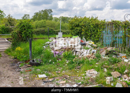Un tas de détritus, gravats et déchets des sous-évaluées les décharges sauvages illégales à côté d'une ligne de chemin de fer à Nursling, Test Valley, Southampton, Hampshire, Royaume-Uni Banque D'Images