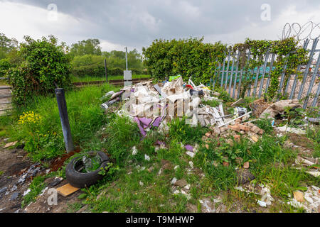 Un tas de détritus, gravats et déchets des sous-évaluées les décharges sauvages illégales à côté d'une ligne de chemin de fer à Nursling, Test Valley, Southampton, Hampshire, Royaume-Uni Banque D'Images